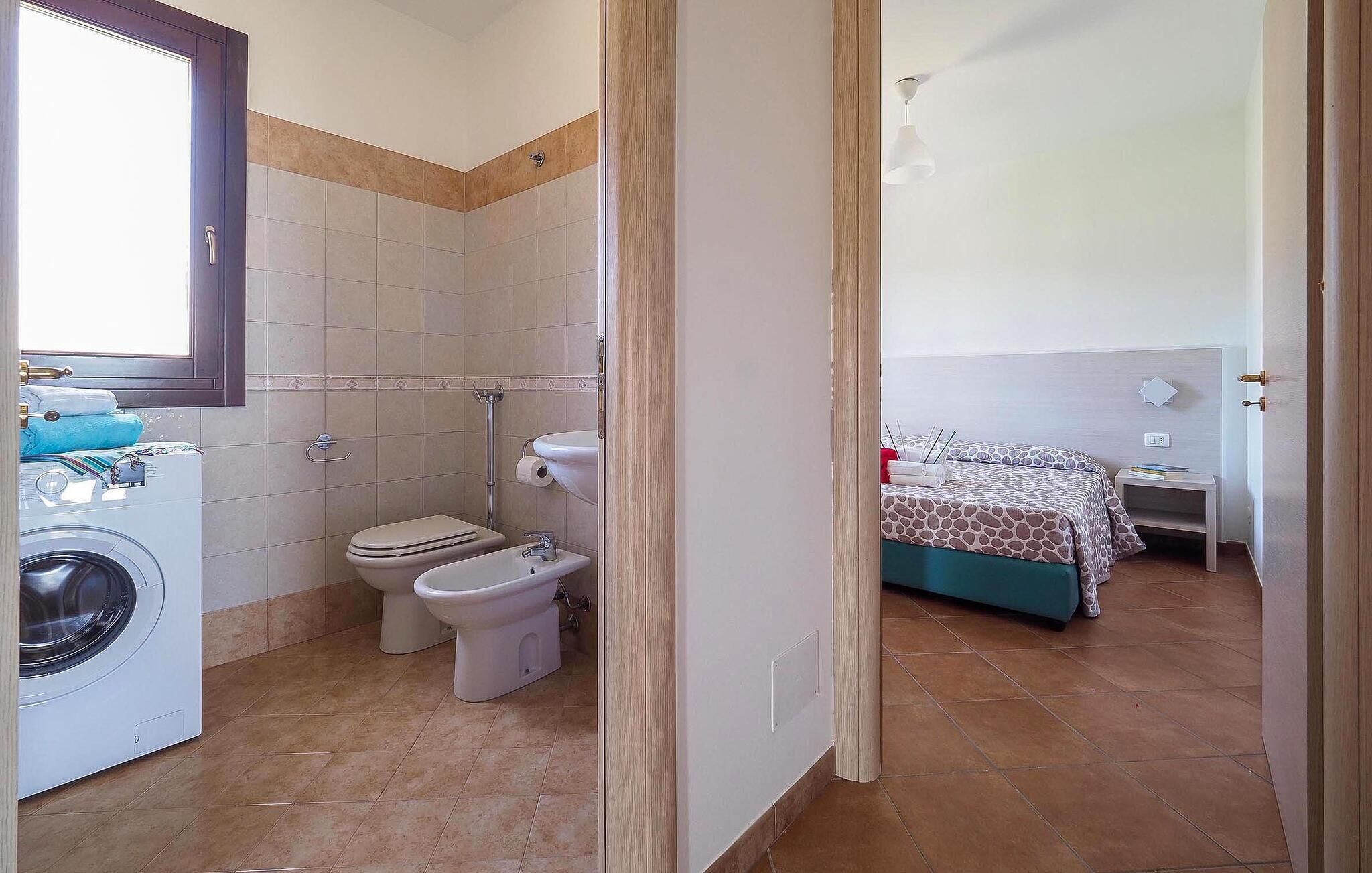 Een badkamer met een wasmachine, twee toiletten en een douche.