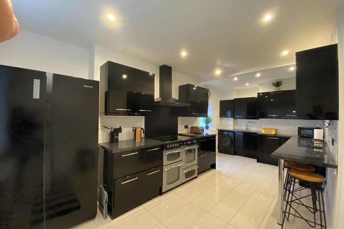 A modern kitchen with black cabinetry, stainless steel appliances, and a central island with stools.