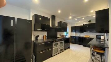 A modern kitchen with black cabinetry, stainless steel appliances, and a central island with stools.