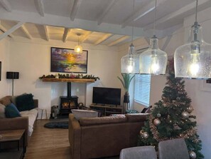 Tunnelmallinen olohuone, jossa on takka, televisio ja joulukuusi.