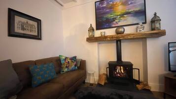 A living room with a sofa, a fireplace, a mounted TV, and a framed picture on the wall.