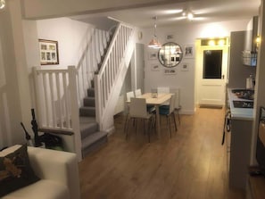 A modern kitchen with a dining area, a staircase, and a small living space. - Downtown cottage in heart of Medieval Conwy (Conwy)