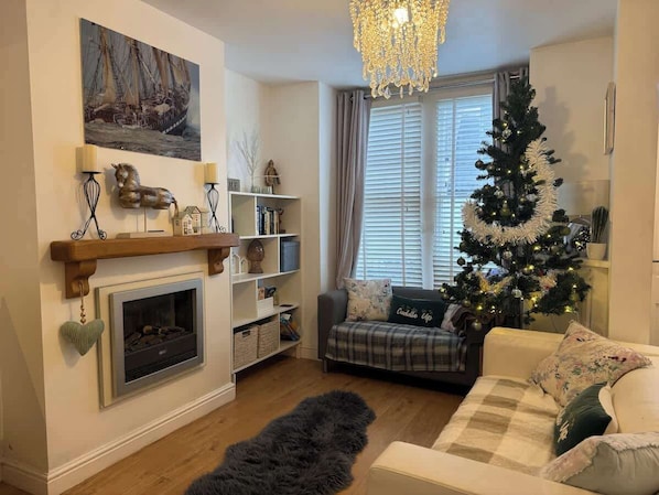 A cozy living room with a fireplace, a Christmas tree, and a sofa. - Downtown cottage in heart of Medieval Conwy (Conwy)