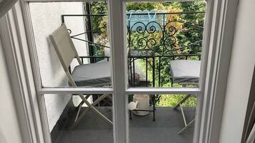 A window with a view of a patio area, including a chair and a table.