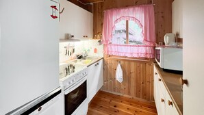 Une cuisine de taille réduite avec des murs en bois, une cuisinière blanche, un évier et un four à micro-ondes.