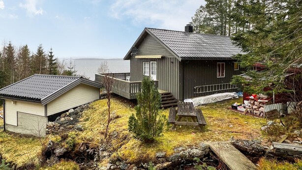 Une cabane avec une terrasse, un petit porche et une vue sur l  ’eau.