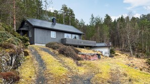 Une maison moderne avec une façade sombre, un toit en pente et une petite terrasse.