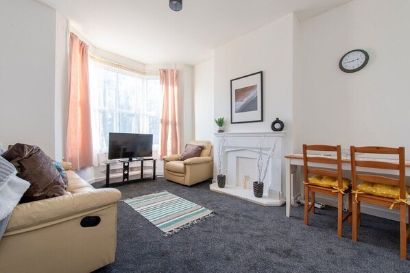 Ein Wohnzimmer mit Sofa, Fernseher, Kamin und Essbereich.