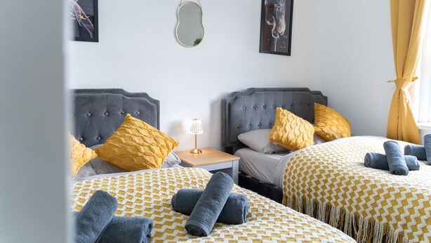 A hotel room with two beds, each with a patterned bedspread, a bedside lamp, and decorative pillows. - Open Mind Property - Southsea with Free Parking (Portsmouth)