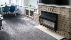 A living room with a fireplace, TV, and dining area with chairs and a table. - Open Mind Property - Southsea with Free Parking (Portsmouth)
