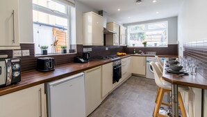 Eine moderne Küche mit weißen Schränken, einer Holz Arbeitsplatte, einem Einbauofen und einem Geschirrspüler.
