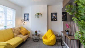 Ein modernes Wohnzimmer mit einem gelben Sofa, einem gelben Sitzsack und einem kleinen runden Tisch mit einer Pflanze.