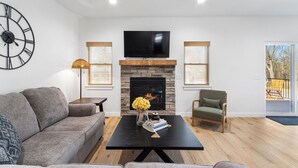 Un salon moderne avec une cheminée, un canapé, une table basse et un téléviseur.