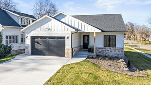 Une maison à deux étages avec un garage, un porche à l’avant et une pelouse bien entretenue.