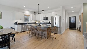 Une cuisine moderne avec des meubles blancs, des appareils en acier inoxydable et un îlot central doté de tabourets de bar.