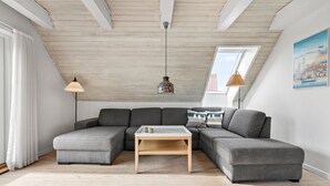 Ein modernes Wohnzimmer mit einer Eckcouch, einem kleinen Holztisch und einem Oberlicht.