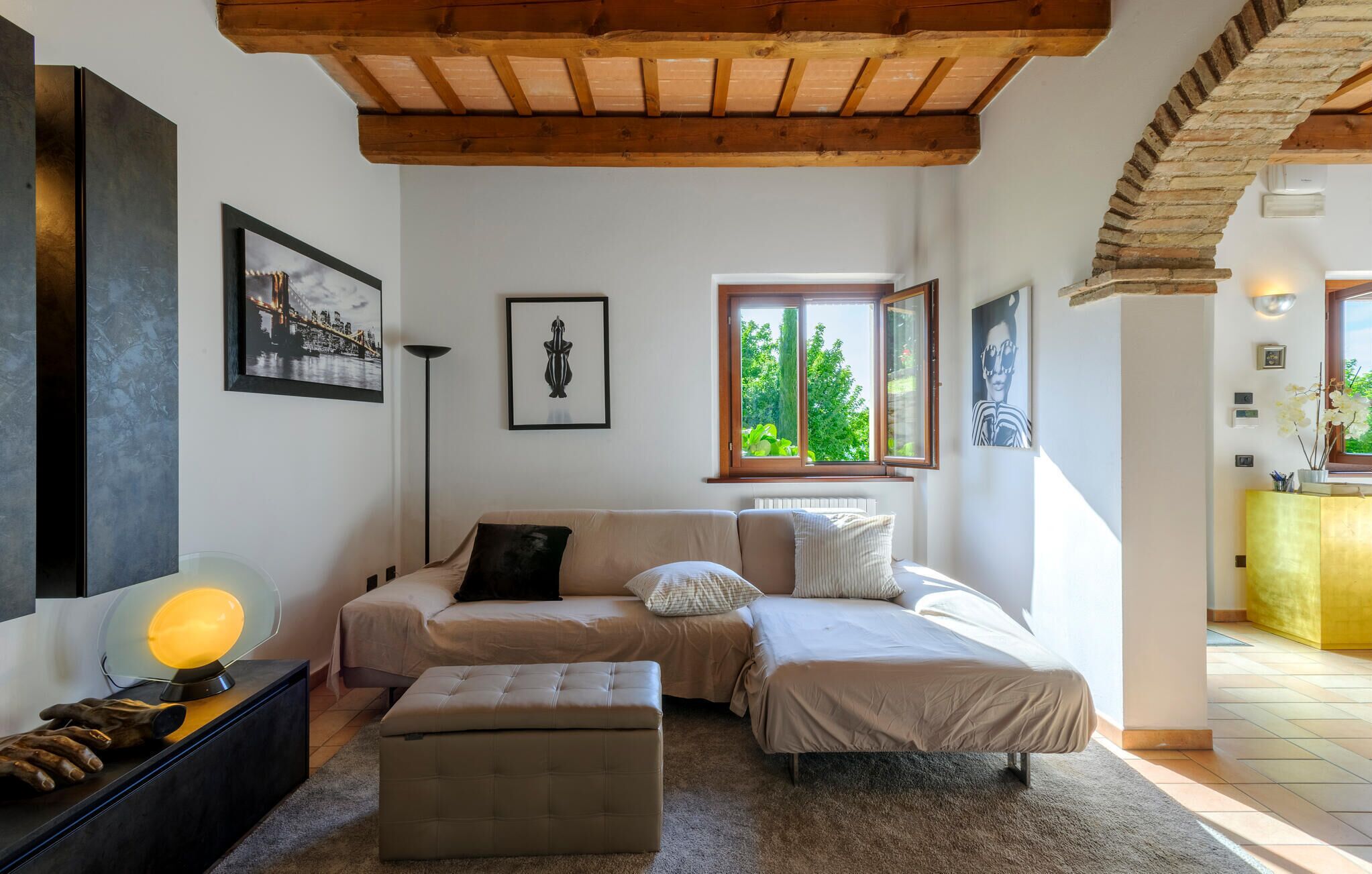 Ein Schlafzimmer mit einem Bett, einer Bank, einer Stehlampe und Kunstwerken an den Wänden.