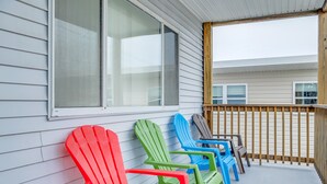 Un portico con poltrone Adirondack colorate e una ringhiera in legno.