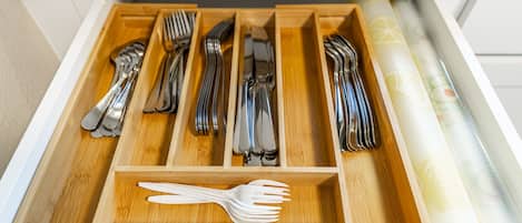 A drawer with multiple compartments containing various utensils.