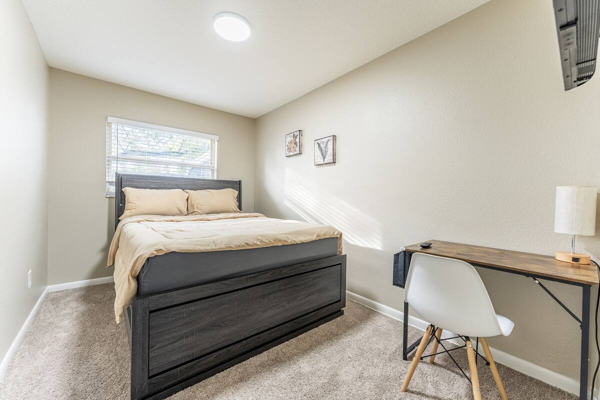 A bedroom with a bed, a desk, and a chair.