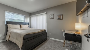 A bedroom with a bed, a desk, and a chair.