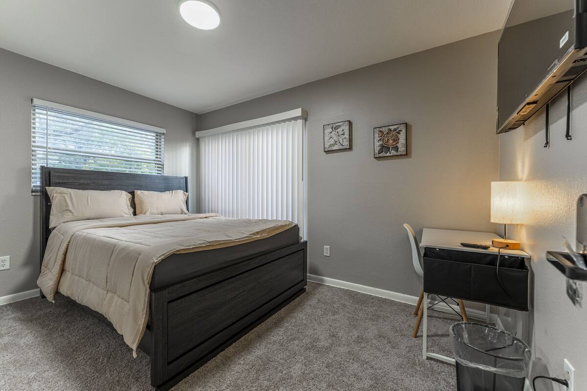 A bedroom with a bed, a desk, and a chair.