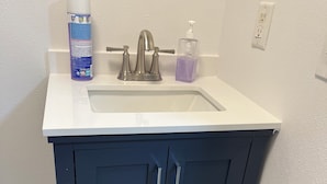 A bathroom with a white sink, dark blue cabinets, and a toilet paper holder.