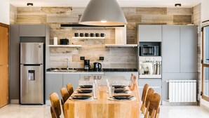 A modern kitchen with a wooden dining table set for six, a built-in oven, and a large pendant light. - Gente del Sur - Fique (Ushuaia)