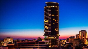 Un grand hôtel de forme cylindrique, à étages multiples, doté de fenêtres illuminées et d’une architecture moderne.