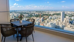 Un balcon avec une table et des chaises, donnant sur un paysage urbain.