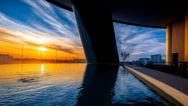 Une vue du coucher de soleil prise depuis l’intérieur d’un pont, avec l’eau calme reflétant le ciel.