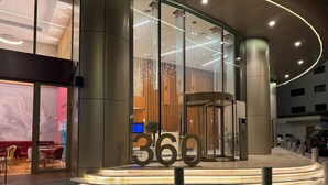 A modern building entrance with a revolving door, glass facade, and a number '360' sign. - WealthyStays: SkyHigh Central (Nicosia)