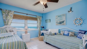 A room with two beds, a desk, and a window with a view. - You cannot get any closer to the beach! 2BR condo (Satellite Beach)