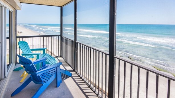 A balcony with a view of the ocean, featuring blue chairs and a concrete floor. - You cannot get any closer to the beach! 2BR condo (Satellite Beach)