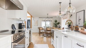Une cuisine moderne avec des meubles blancs, des appareils en acier inoxydable et un îlot central doté de sièges.