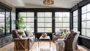 Une pièce chaleureuse avec une grande fenêtre, un plancher en bois et des meubles en osier.