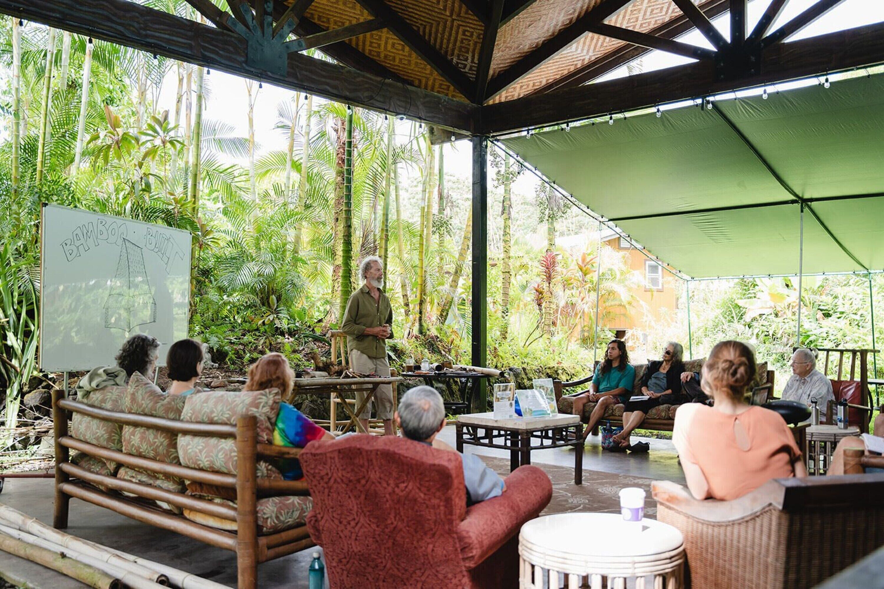 An outdoor seating area with bamboo furniture, a whiteboard, and a presentation.