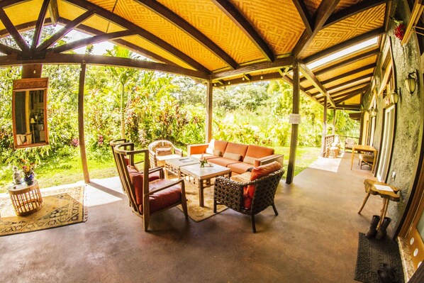 Un patio techado al aire libre con un sofá, sillas y una mesa.