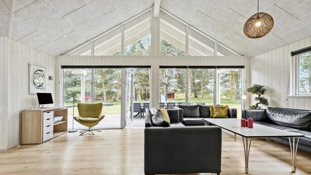 A spacious living area with a modern design, featuring a large sofa, a dining table, and a yellow chair.
