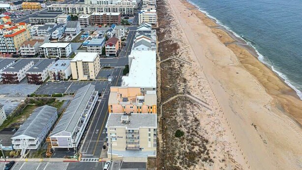 An aerial view of a coastal town with a beachfront, buildings, and a road.