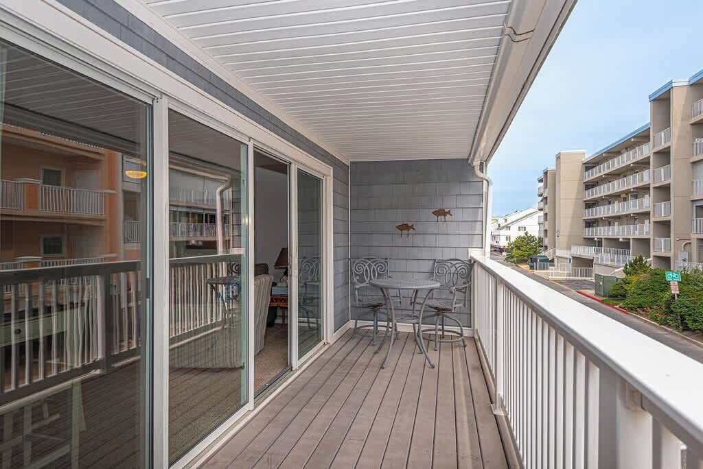 A balcony with a view of neighboring buildings, a table and chairs, and a railing.