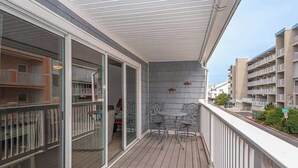 A balcony with a view of neighboring buildings, a table and chairs, and a railing.
