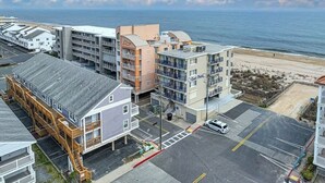 A coastal hotel with multiple buildings, a parking lot, and a view of the beach.