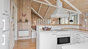 A modern kitchen with wooden walls, a built-in oven, and white cabinetry. - Beautiful home in Sydals with kitchen (Sydals)