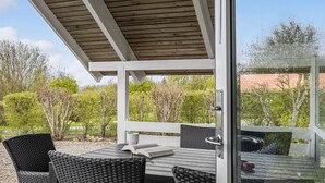 A covered outdoor seating area with a table and chairs, surrounded by greenery and trees. - Beautiful home in Sydals with kitchen (Sydals)