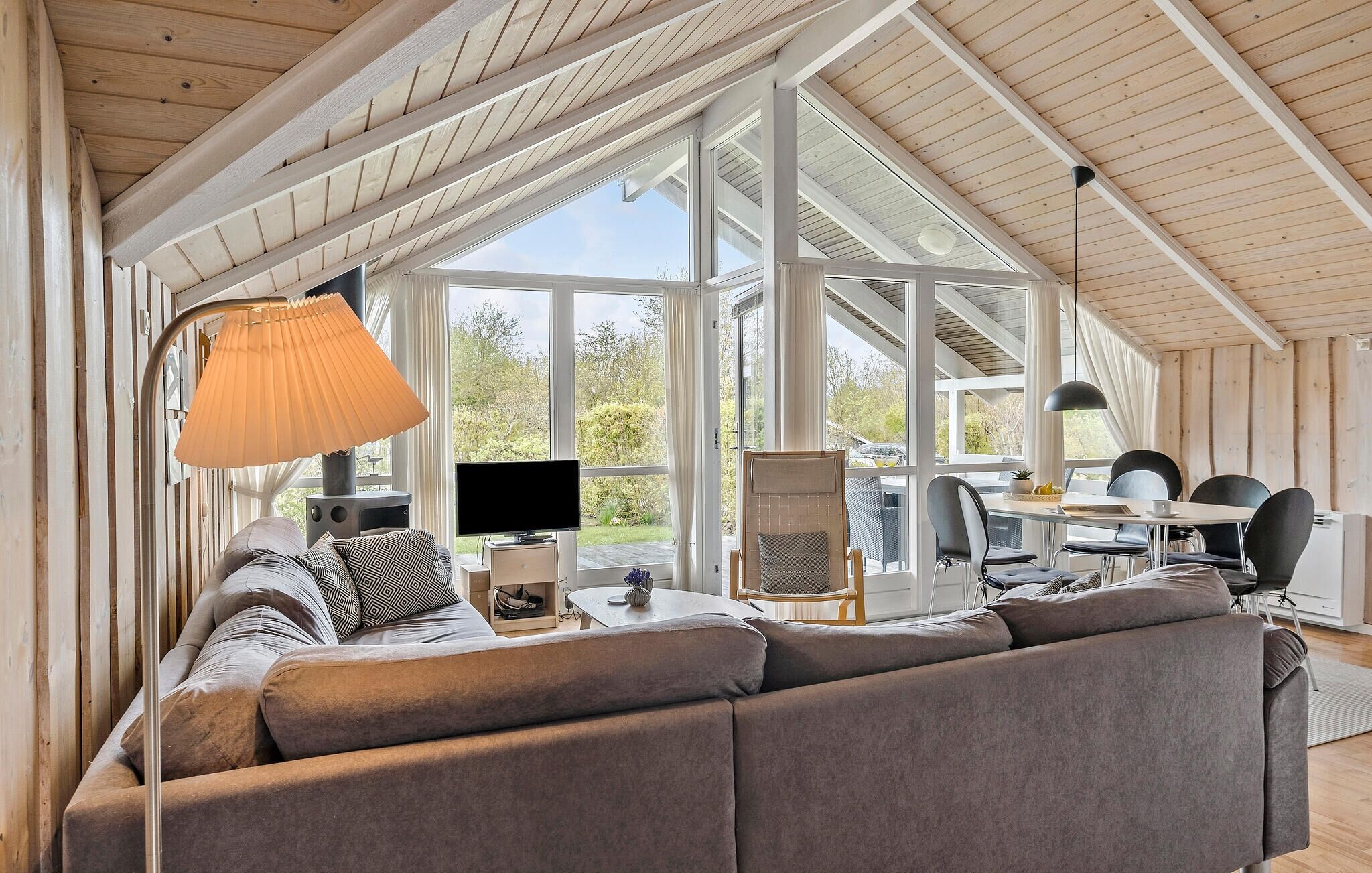 A cozy living room with a large sofa, a TV, and a dining area with a table and chairs.