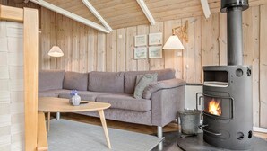 A cozy room with a grey sofa, a small round table, and a wood-burning stove. - Beautiful home in Sydals with kitchen (Sydals)
