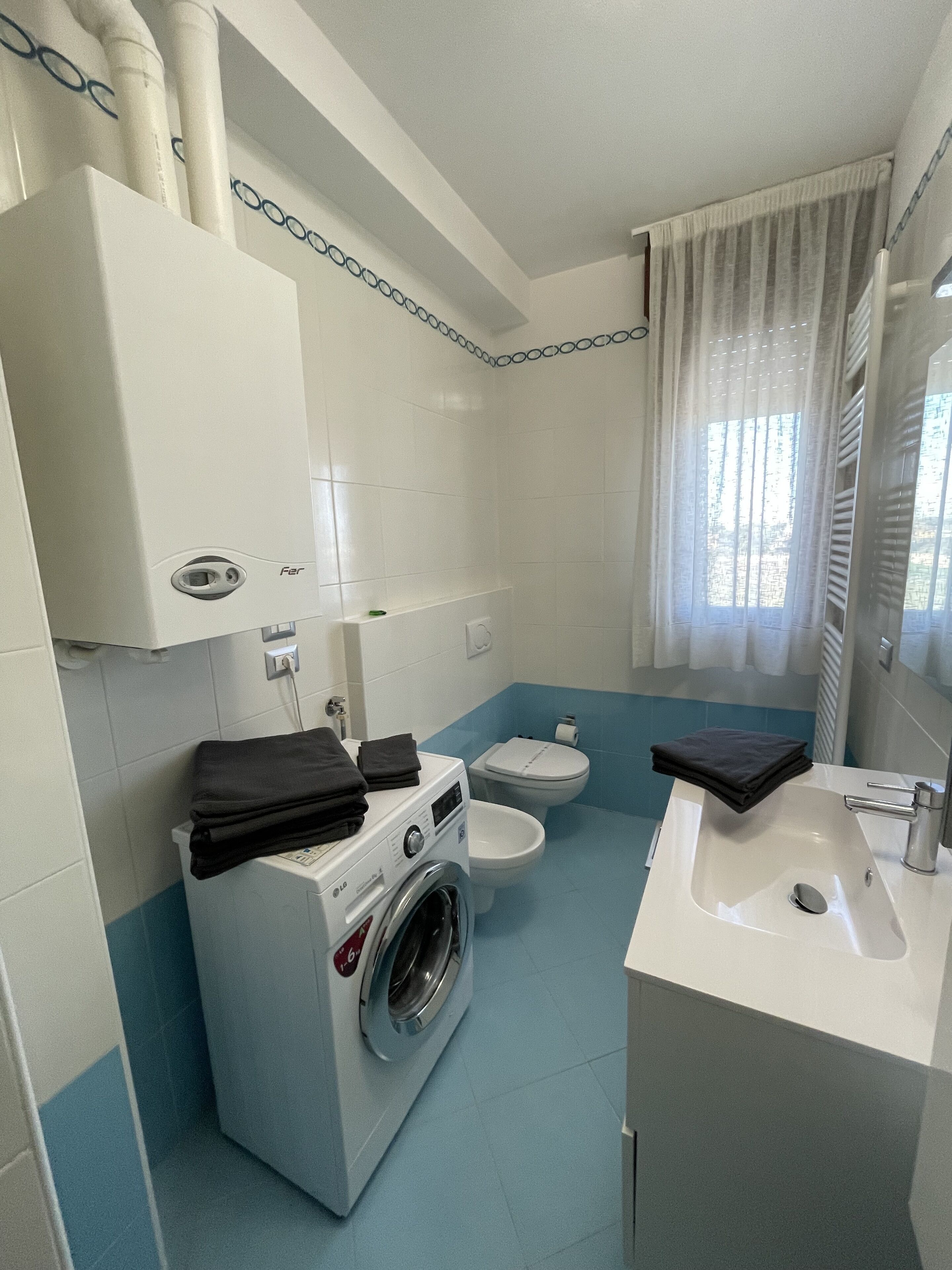 A compact bathroom with a washing machine, toilet, and sink.