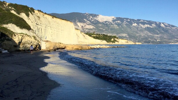 Une plage côtière bordée de falaises, sous un ciel dégagé.