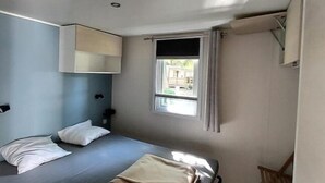 A bedroom with a bed, a window, a chair, and a ceiling fan. - Mobil Home - N025 (Bootzheim)